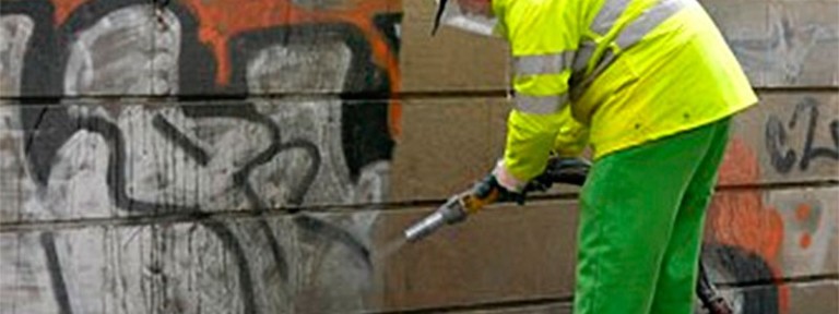 Operario limpiando graffitis en una pared