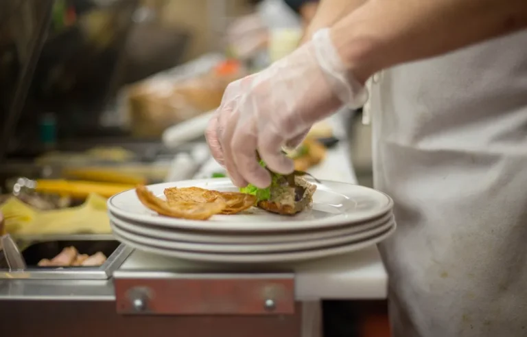 Cocinero con guantes preparando platos en una cocina profesional