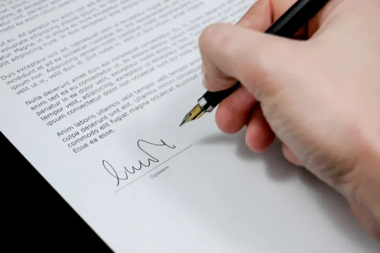 Mano firmando un documento con un bolígrafo