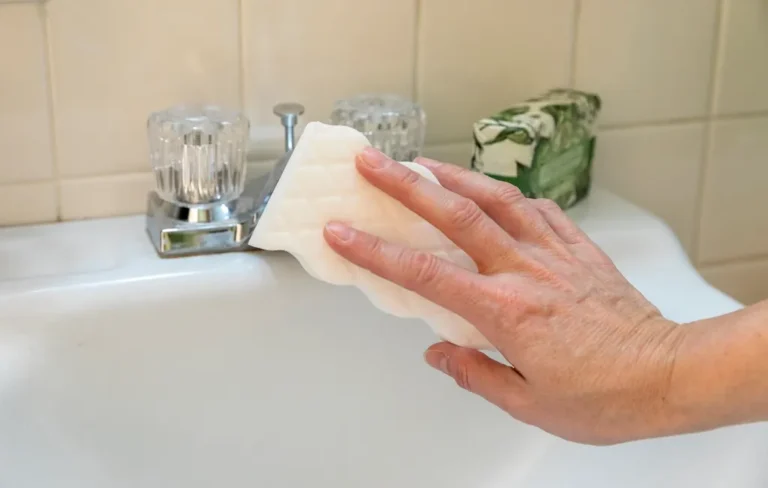 Mano limpiando un lavabo con una esponja