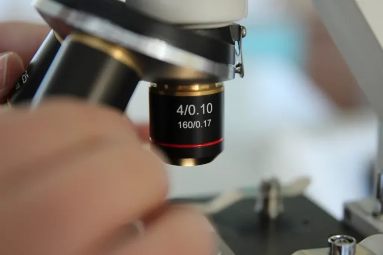Manos ajustando un microscopio