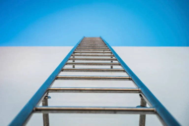 Escalera azul apoyada en una pared blanca