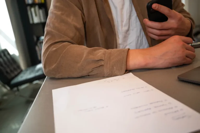 Mano escribiendo sobre papeles de trabajo