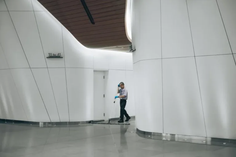 Trabajador de limpieza con guantes azules en el vestíbulo de un edificio moderno