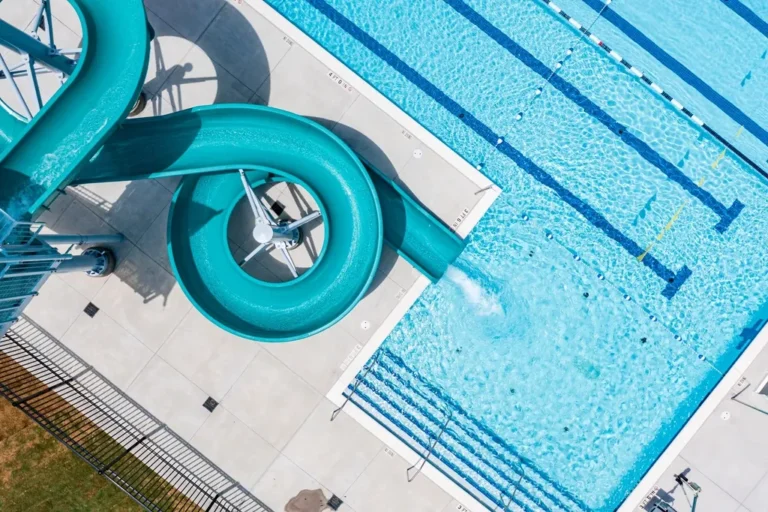Vista aérea de una piscina pública con calles de natación y un tobogán